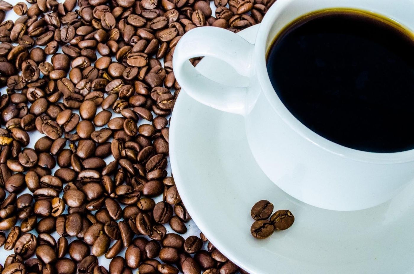 Imagem ilustrativa: xícara de café preto sobre grãos