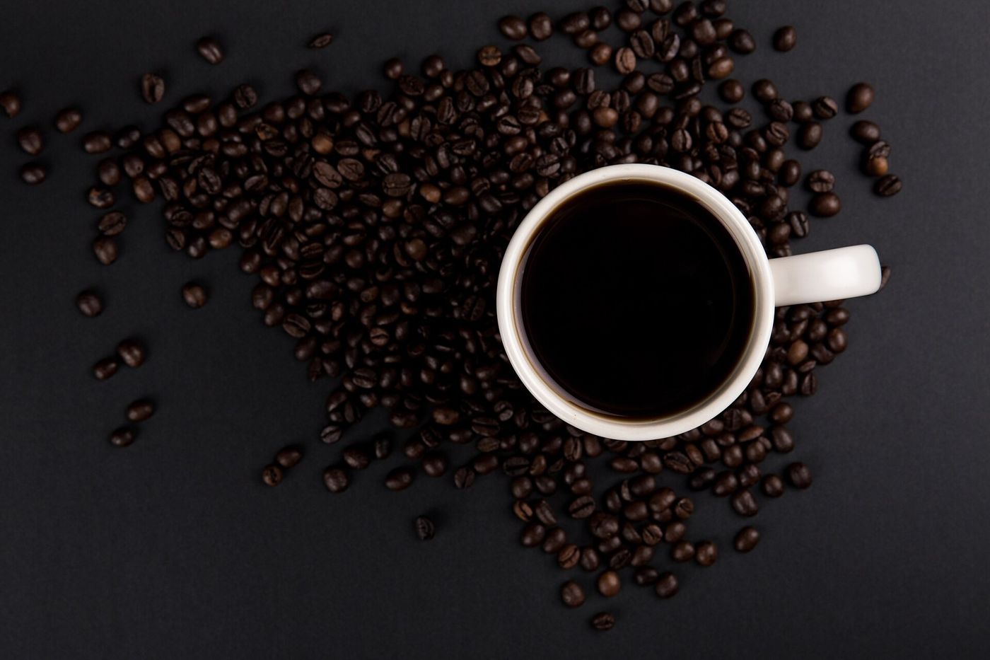 Imagem ilustrativa: xícara de café preto entre grãos