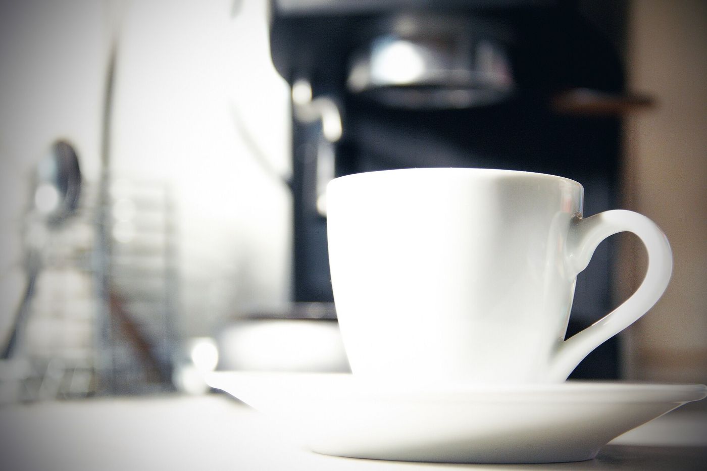 Imagem ilustrativa: xícara branca ao lado da máquina de café