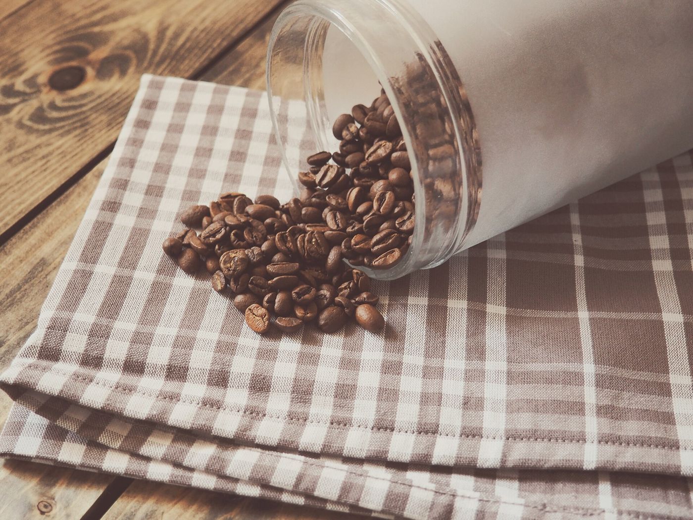 Imagem ilustrativa: grãos de café sobre tecido xadrez