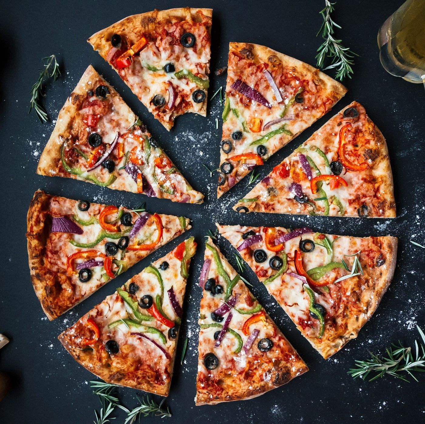 Imagem ilustrativa: pizza fatiada sobre fundo escuro
